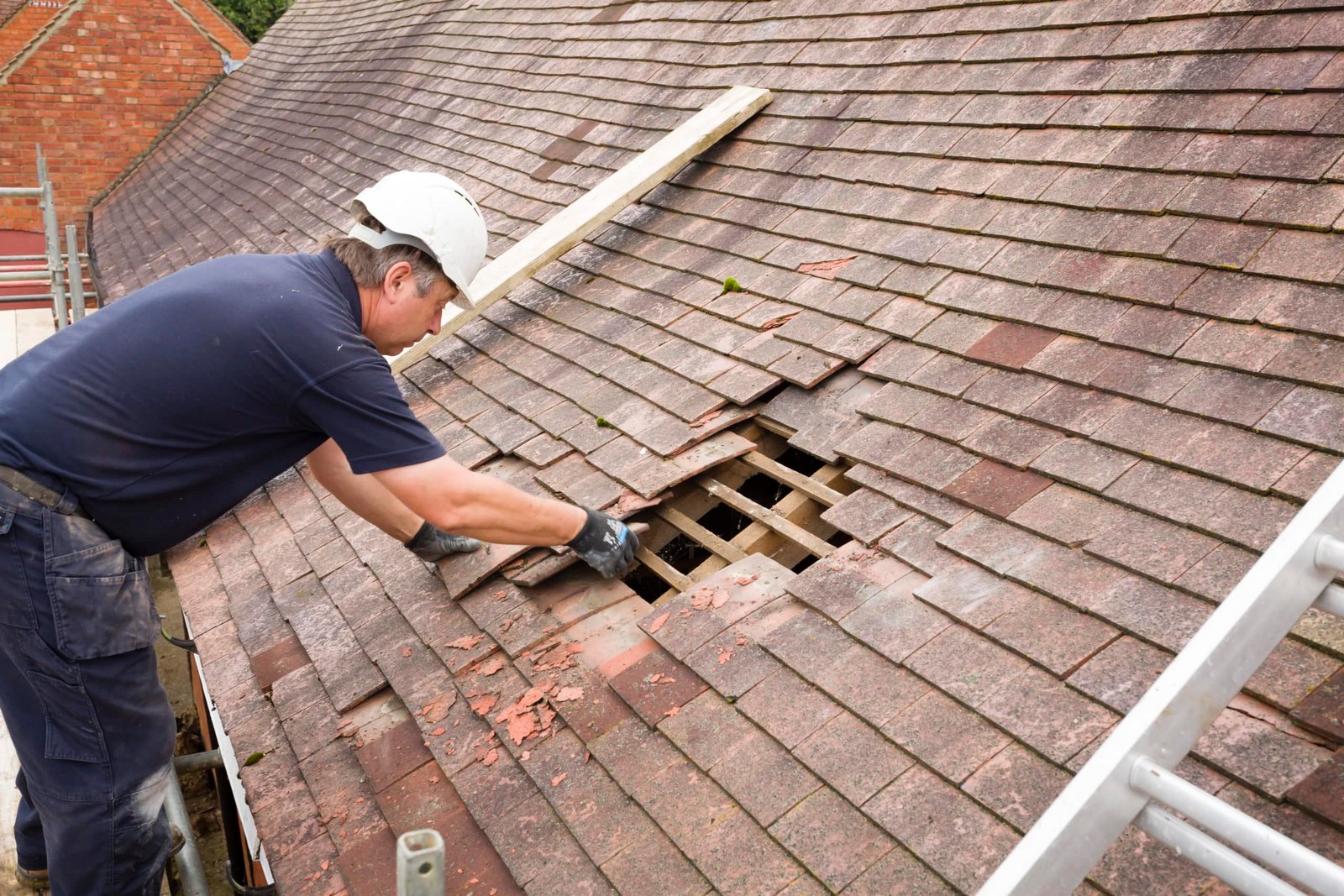 Home builder removing old clay tiles from a pitched roof uk